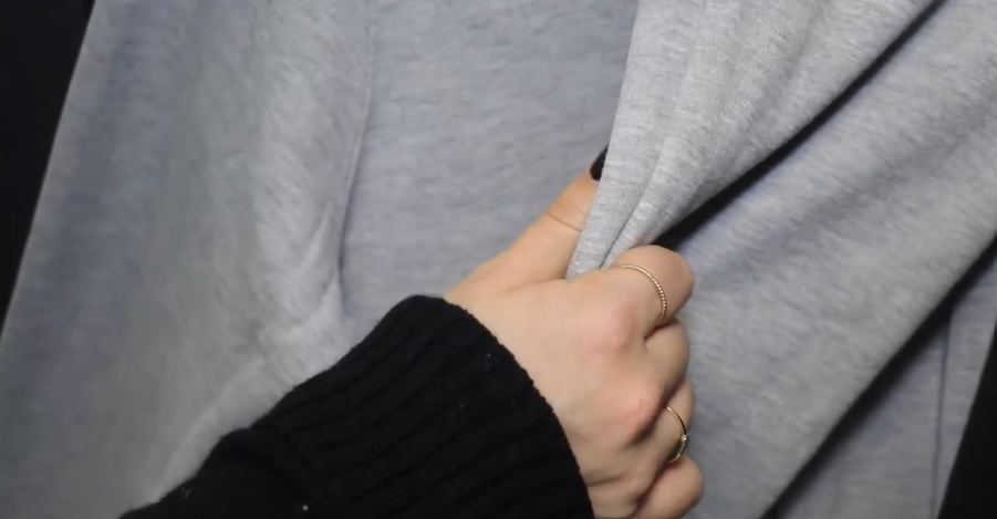 A hand touching a grey textile fabric.