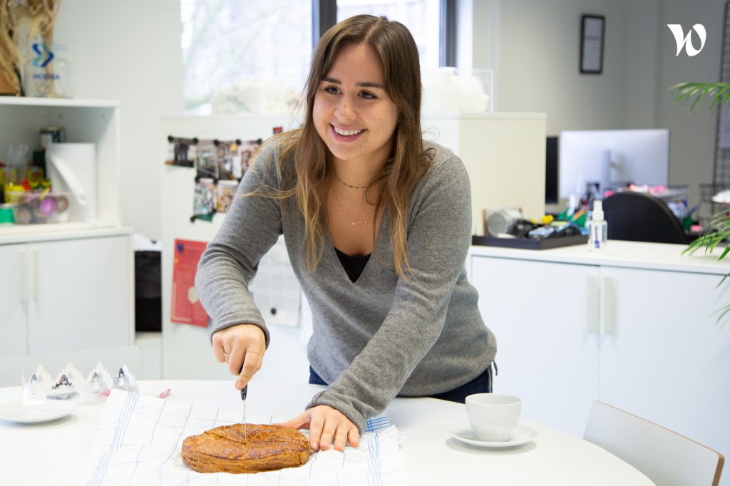 Luna smiling and cutting a pie in the office.