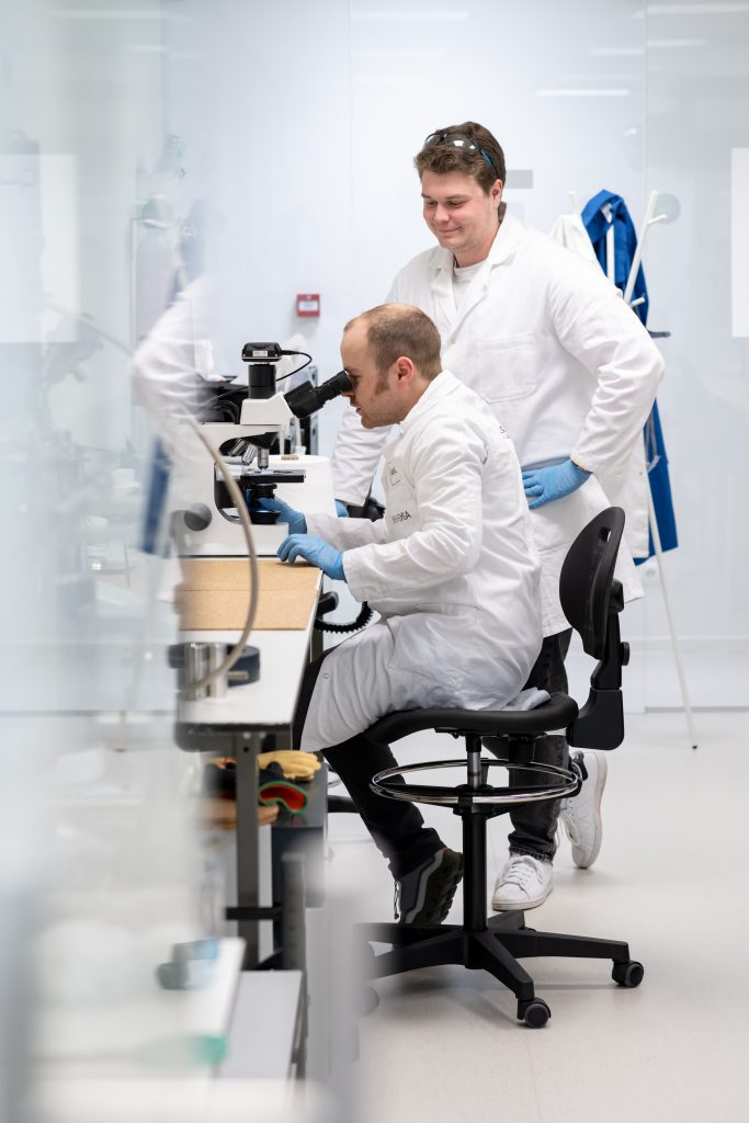 Niccolo and Gabriel working in the lab. Gabriel is looking at something in the microscope.