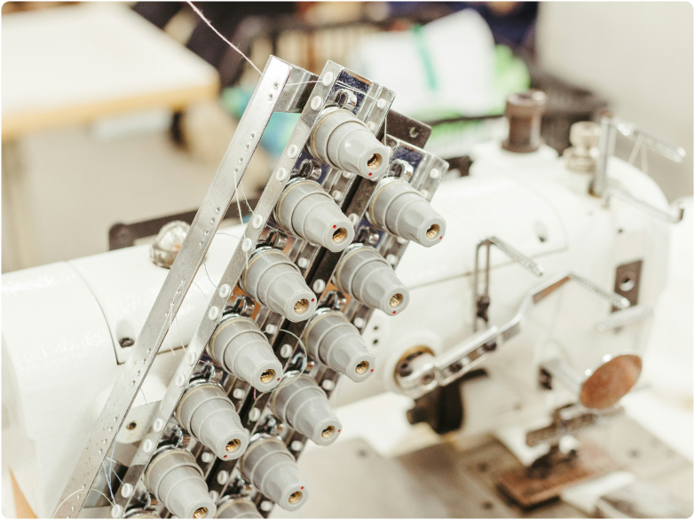 A close-up of an industrial sewing machine with multiple thread spools attached.