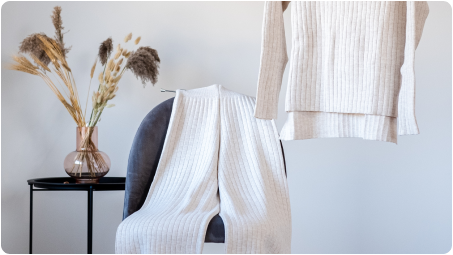 Beige knit sweater and pants displayed on a chair showing the apparel applications of NOOSA™'s bio-based and recyclable fiber.