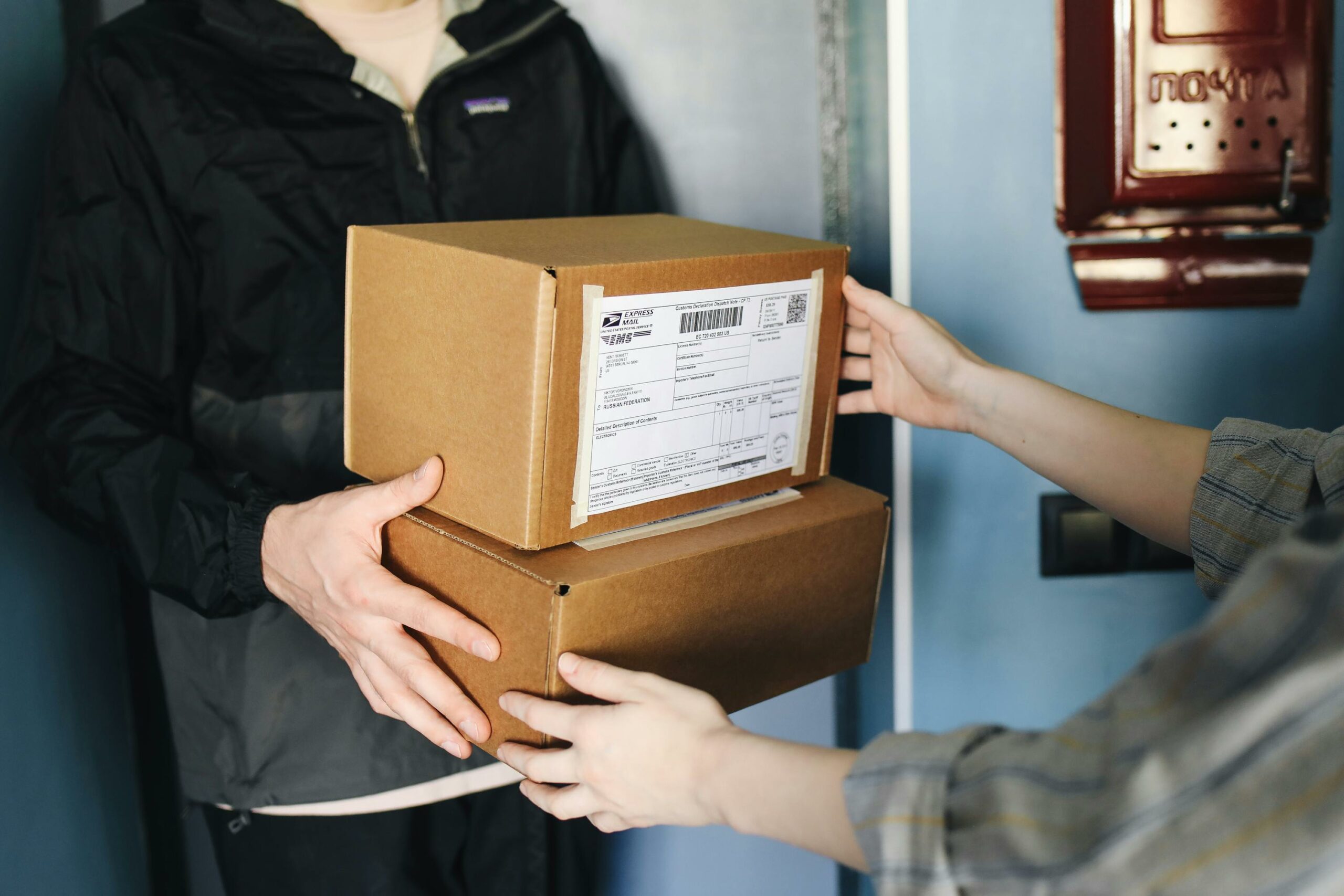 One person is delivering a package to another at a doorway.