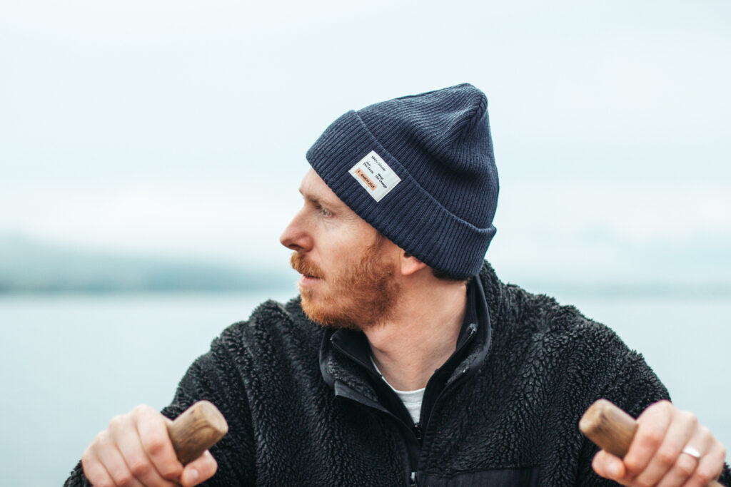 Man wearing Nikin NOOSA navy beanie on a lake